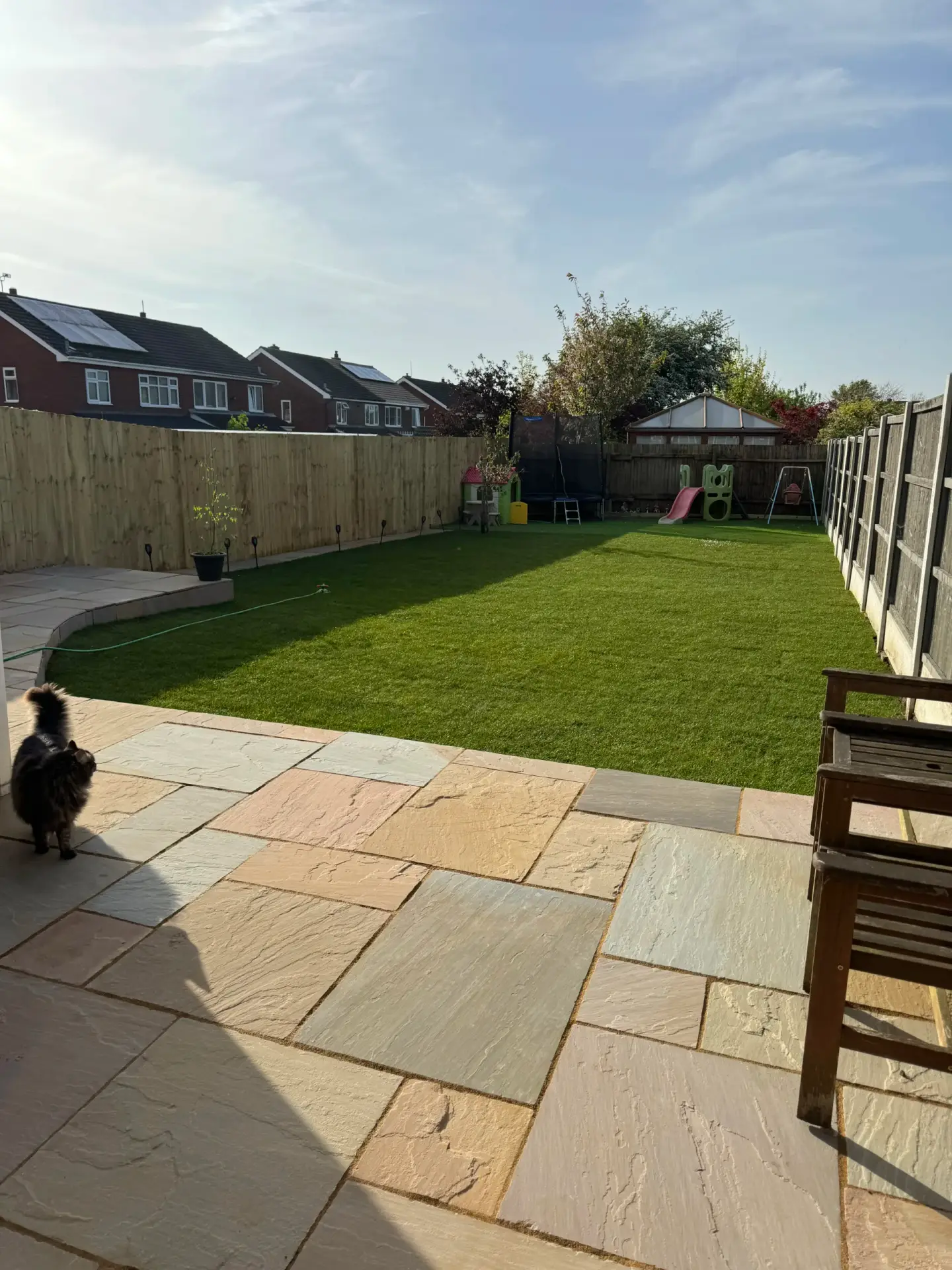 New turf lawn beyond a paved patio with timber fencing down both sides, laid by landscape gardeners in Lincolnshire