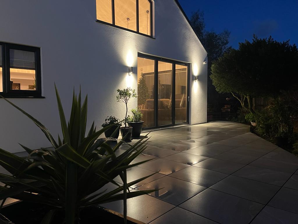 Porcelain patio with wall lighting at night, installed by Reshape Landscaping in Scotter