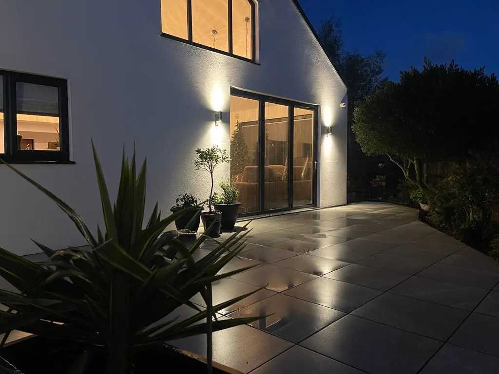 Porcelain patio with wall lighting at night, installed by Reshape Landscaping in Scotter