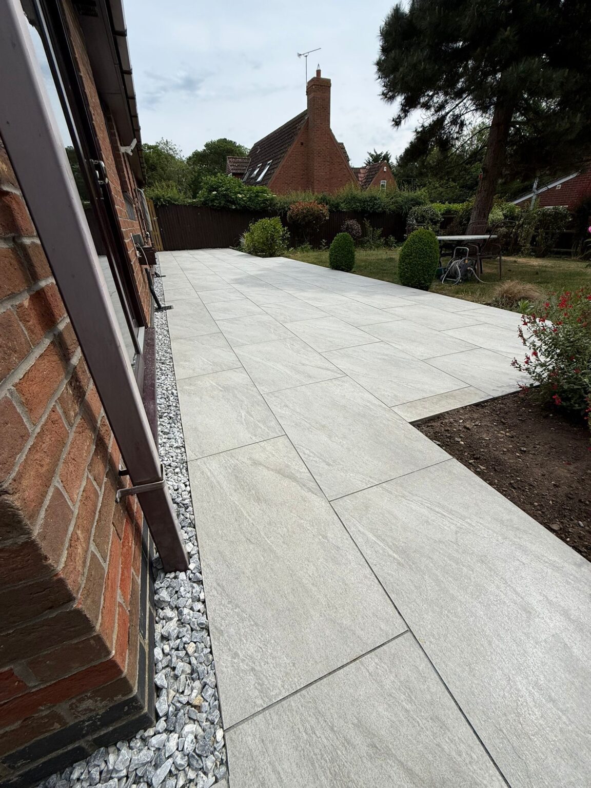 Light grey porcelain paving with a gravel strip along the house, laid by Reshape Landscaping in Lincoln