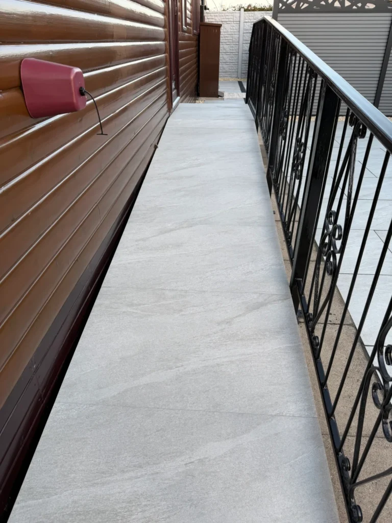 Light grey porcelain ramp installation in Gainsborough The Elms by landscape gardeners, featuring smooth large-format tiles and low-maintenance artificial lawn